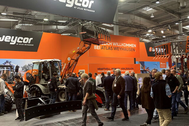 Messestand von Weycor mit Radladern und Besuchern auf einer Fachmesse.