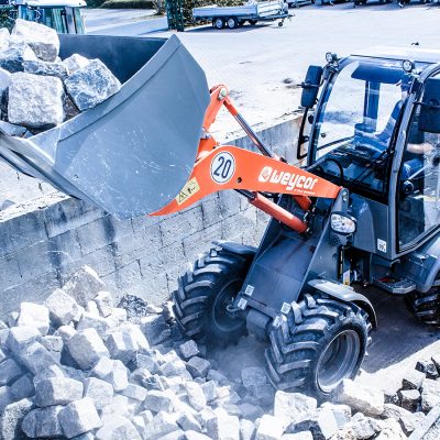 Weycor Radlader AR 380 beim Bewegen von großen Natursteinen in einer Baustofflagerstätte, Frontansicht leicht von oben.