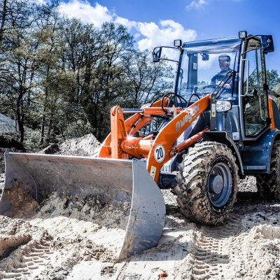 Weycor Radlader auf Baustelle, beladen mit Sand, Fahrer in Kabine.