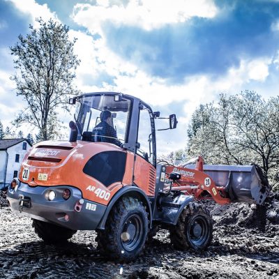 Weycor AR 400 Radlader mit Erde beladen auf Baustelle, Fahrer in Kabine.