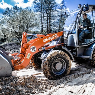 Weycor AR 400 Radlader bei Erdarbeiten, Fahrer in Kabine, Schaufel im Boden.