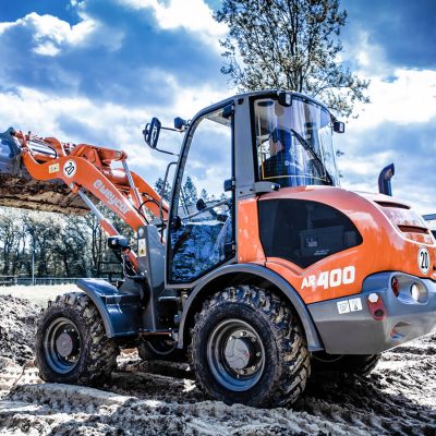 Weycor AR 400 Radlader mit erhobener Schaufel auf Baustelle, Fahrer in Kabine.