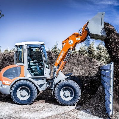 Weycor Radlader AR 420 kippt Material auf Holz-Halden.