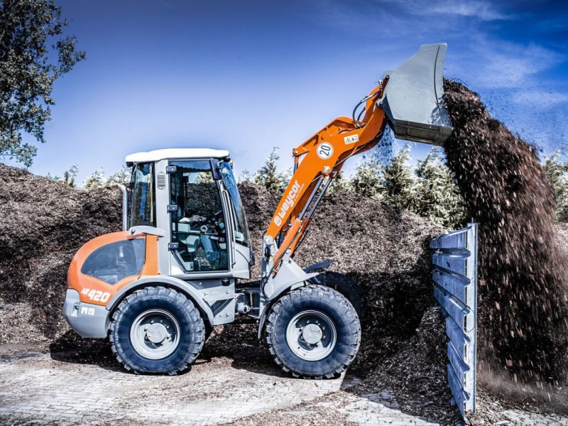 Weycor Radlader AR 420 kippt Material auf Holz-Halden.
