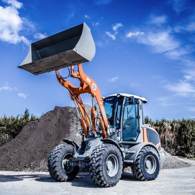 Weycor Radlader AR 480 hebt Schaufel vor Erdhaufen.