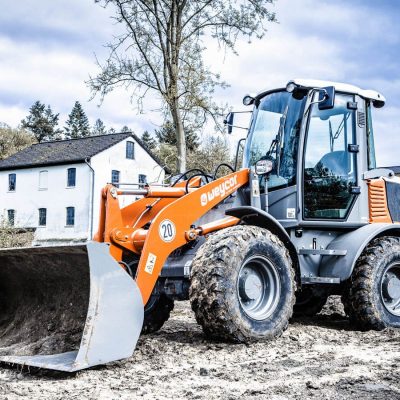 Weycor Radlader AR 480 mit Schaufel auf Baustelle vor Haus.