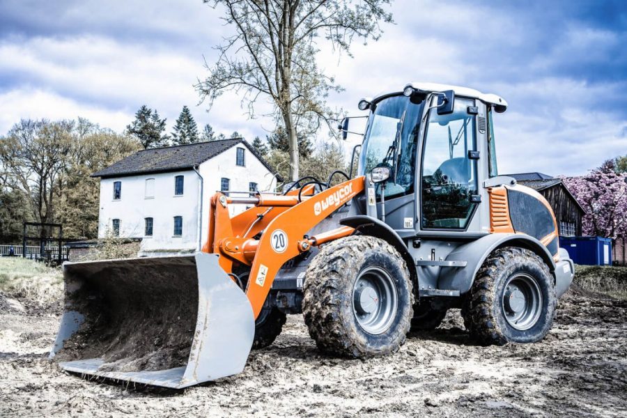 Weycor AR 480 wheel loader with shovel on construction site in front of house.