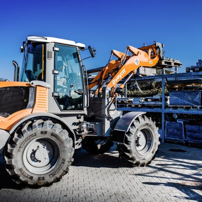 Weycor Radlader AR 530 hebt Paletten auf ein Regal im Außenlager.