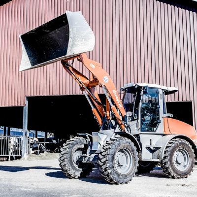 Weycor Radlader AR 560 vor einem Stallgebäude mit angehobener Schaufel.