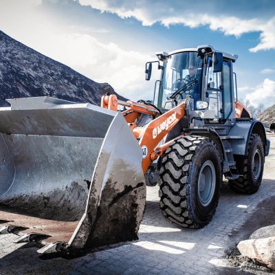 Weycor Radlader mit großer Schaufel auf Baustelle mit Kieshaufen.