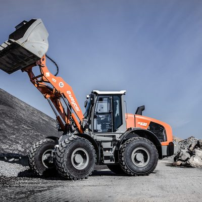 Weycor AR 620 Radlader mit gehobener Schaufel vor Schotterhaufen.