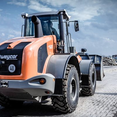 Weycor AR 620 Radlader mit gehobener Schaufel vor Schotterhaufen.