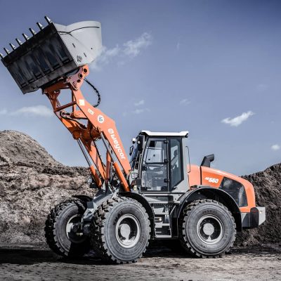 Weycor AR 660 Radlader mit hoch angehobener Schaufel vor Erdhügeln.