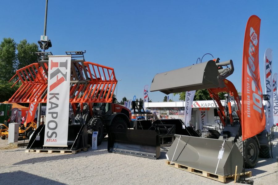 Weycor Radlader und Anbaugeräte auf einer Außenausstellung von KAPOS Atlas, mit Bannern und Werbefahnen.